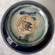 Load image into Gallery viewer, Vintage mid-century "Anemone" perfume bottle with stopper. Hand painted in the slip glaze technique in shades of purple, pink and green on a deep cobalt blue ground. Produced by Moorcroft Pottery, circa 1928-1953. In excellent condition, no chips, cracks or repairs, crazing present. Bottom shows impressed signature of Walter Moorcroft, "MADE IN ENGLAND" and Royal Warrant paper label - 'Potter To HM The Queen'. Measures 4" x 5-1/2"