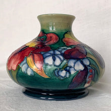 Load image into Gallery viewer, Gorgeous vintage mid-century hand painted squat flower vase in the "Orchid" pattern on green ground, hand painted in shades of red, yellow, purple and blue using the slip glaze technique. Made by Moorcroft Pottery in Stoke-on-Trent, England, circa 1950. In excellent condition, no chips, cracks or repairs, crazing present. Initials of Walter Moorcroft in blue, impressed marks "MOORCROFT" and "MADE IN ENGLAND". Measures 3-1/4" high