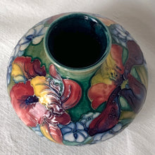 Load image into Gallery viewer, Gorgeous vintage mid-century hand painted squat flower vase in the "Orchid" pattern on green ground, hand painted in shades of red, yellow, purple and blue using the slip glaze technique. Made by Moorcroft Pottery in Stoke-on-Trent, England, circa 1950. In excellent condition, no chips, cracks or repairs, crazing present. Initials of Walter Moorcroft in blue, impressed marks "MOORCROFT" and "MADE IN ENGLAND". Measures 3-1/4" high