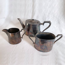 Load image into Gallery viewer, Vintage Victorian style silver plated teapot, creamer and sugar etched with bow and ribbon details and great patina. Ideal for mad hatters tea party, vintage decor or props. Would be perfect for a 'shabby chic' decor scheme or repurposed for a floral arrangement, or redesign as your imagination allows.
Teapot is missing lid finial.
In as found condition.