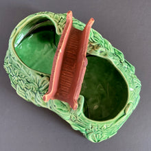 Load image into Gallery viewer, A vintage ceramic planter featuring a rusty red bridge over a green pond with impressed brick wall and stairs, and floral details. Crafted by Shawnee Pottery, USA, 1950s. Create a unique garden with this unique planter!
In vintage condition with minor flea bites to the bridge.
Measures 9 x 5 3/4 x 4 3/4 inches