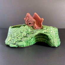 Load image into Gallery viewer, A vintage ceramic planter featuring a rusty red bridge over a green pond with impressed brick wall and stairs, and floral details. Crafted by Shawnee Pottery, USA, 1950s. Create a unique garden with this unique planter!
In vintage condition with minor flea bites to the bridge.
Measures 9 x 5 3/4 x 4 3/4 inches