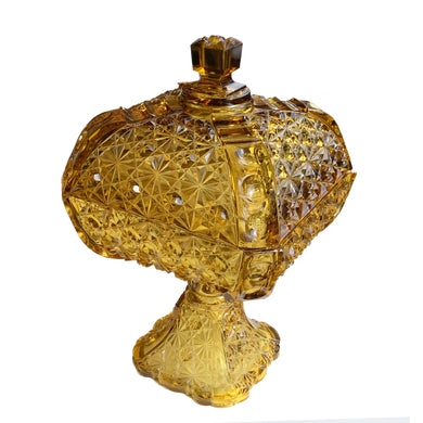 Antique amber Daisy and Button with Thumbprint glass lidded compote. Crafted by Adams & Co, USA, 1861 to 1891. This impressive compote is perfect for candies or as a decor piece....it catches the light beautifully!

In as found condition with chips to the rim of the lid, the base is in excellent condition, no chips.

Measures 6 1/2 x 6 1/2 x 11 1/2 inches