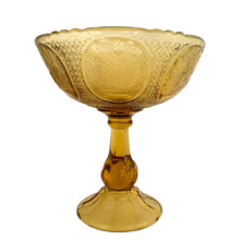 Load image into Gallery viewer, Antique Art Nouveau style amber pressed glass pedestal compote featuring 6 floral medallions, diamond star pattern on a thick pedestal and foot. Catalog number 1180. Crafted by Zabcowice Glassworks, Poland, 1910. This piece would look grand filled with fruit as a table centrepiece or fill with pine cones for display on your entranceway table....the decor possibilities are endless!

In excellent condition, no chips.

Measures 9 x 9 1/2 inches
