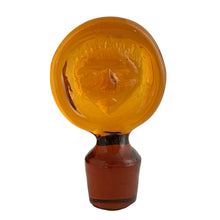 Load image into Gallery viewer, Close-up of stamped face stopper on Erik Höglund amber glass decanter
