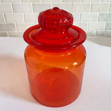 Load image into Gallery viewer, Striking amberina hand blown vintage apothecary canister jar with ground lid which is topped with an embossed flower. Takahashi Glass, Japan, circa 1970. This fabulous colour will liven up any room and it glows under black light! In good vintage condition. There is chipping chips to the inside rim of the lid see photos. There are bubbles in the glass typical of the manufacturing process. Measures 6 3/4 x 10 inches
