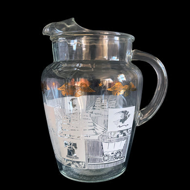 Vintage 64 oz clear glass ice lip pitcher with ribbed handle features a block printed design early American heritage scenes in white with a band of gold eagles and stars. Crafted by Anchor Hocking, USA, 1950s. A great way to show off your patriotic style!

In excellent condition, no chips, minor wear to the gold.

Measures 6 1/2 x 5 1/2 x 9 inches

Capacity 64 ounces