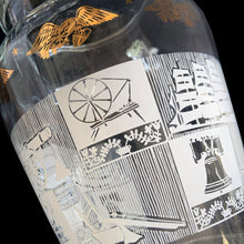 Load image into Gallery viewer, Vintage 64 oz clear glass ice lip pitcher with ribbed handle features a block printed design early American heritage scenes in white with a band of gold eagles and stars. Crafted by Anchor Hocking, USA, 1950s. A great way to show off your patriotic style!

In excellent condition, no chips, minor wear to the gold.

Measures 6 1/2 x 5 1/2 x 9 inches

Capacity 64 ounces
