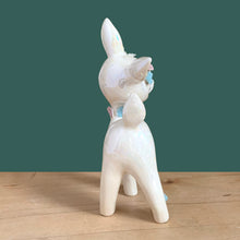Load image into Gallery viewer, Adorable vintage mid-century era anthropomorphic deer ceramic figurine, glazed in iridescent white with blue rhinestone eyes, pink and blue flowers and gold gilt spaghetti details. Crafted by&nbsp;Lefton, Japan, circa 1950s. This sweet-faced deer is sure to delight everyone and it will make a wonderful addition to your Christmas holiday decor!

In good vintage condition. There is a chip to one blue flower, but otherwise excellent. Marked Japan and number 5845.

Measures 3 1/2 x 2 1/2 x 7 inches
