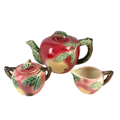 Rare Find! Sweet vintage mid-century era majolica style figural apple shaped ceramics, including a teapot, creamer and covered sugar featuring brown branch handles and green leaves. Crafted by Metroware, Japan, circa 1940s. Perfect to add kitsch style to your kitchen decor. In excellent used vintage condition, free from chips, with interior staining and crazing. Measures 8 1/2 x 4 3/4 x 5 3/4 inches