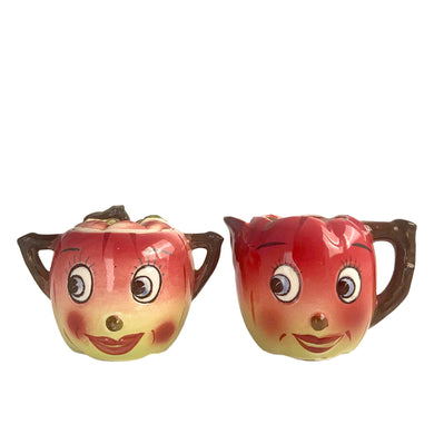 Adorable hand painted anthropomorphic apple face creamer and covered sugar. Crafted by PY, Japan, 1950s. A sweet mid-century kitschy set makes a great addition to your ceramics collection and kitchen decor!

In excellent vintage condition, no chips/cracks, normal crazing present.

Creamer measures 3 3/4 x 3 1/4 inches

Sugar measures 3 1/4 x 3 3/8 inches
