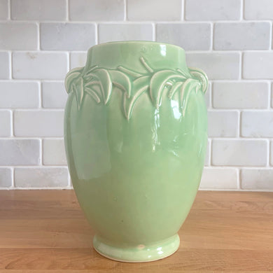 Vintage mid-century gloss aqua handled vase with embossed leaves. Crafted by McCoy Pottery, 1948. This lovely vase is must for any art pottery collector!

In excellent condition, no chips/cracks/repairs, crazing commensurate with age and manufacturing glaze pops. Maker's mark on the bottom.

Measures 5 1/2 x 8 inches