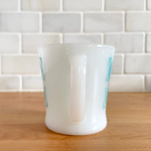 Load image into Gallery viewer, Highly collectible vintage Fire-King Ware milk glass mug with two rows of turquoise rings, D-handle. Crafted by Anchor Hocking, USA, 1960s. A must-have for any Fire-King collector!

In excellent condition, no chips, cracks or repairs. Paint is vibrant and shiny.

Measures 3 1/4 x 3 3/8 inches
