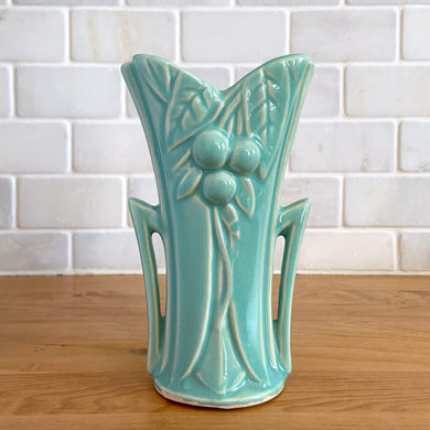 Vintage Art Deco aqua split rim leaf and berries handled vase 104. Crafted by McCoy Pottery, 1948. This rare piece is must for any art pottery collector! A lovely way to enhance your home's decor or give as a gift!

In excellent vintage condition, no chips/cracks/repairs. Typical age-related crazing, manufacturer's glaze pops. Unmarked.

Measures 3 5/8 x 2 1/2 x 5 3/4 inches