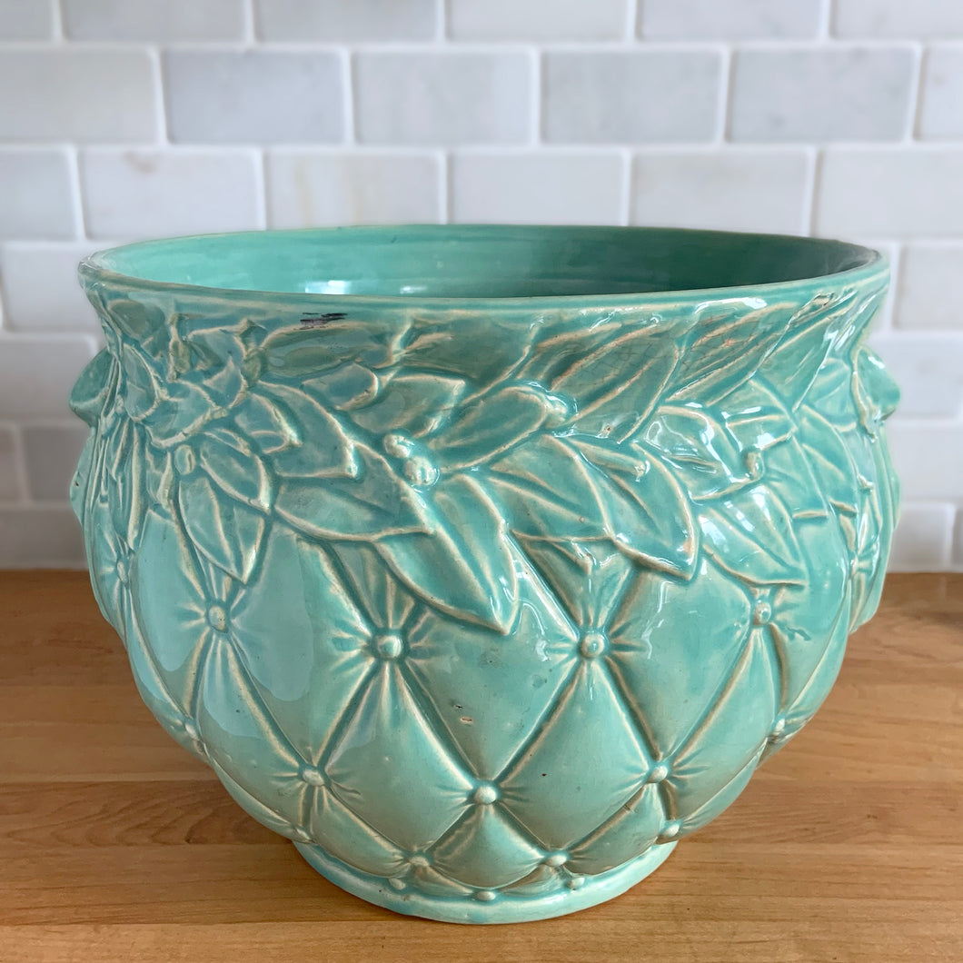 Large vintage aqua gloss glazed Tierra Cushion jardiniere planter pot, features an overlapping floral leaf rim and diamond quilted body with ribbon handles. Crafted by McCoy Pottery, USA, 1950s. A must-have for any McCoy collector or container gardener!

In excellent condition, no chips/cracks/repairs, manufacturer's glaze pops. Maker's mark.

Measures 10 3/8 x 8 1/2 inches