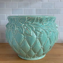 Load image into Gallery viewer, Large vintage aqua gloss glazed Tierra Cushion jardiniere planter pot, features an overlapping floral leaf rim and diamond quilted body with ribbon handles. Crafted by McCoy Pottery, USA, 1950s. A must-have for any McCoy collector or container gardener!

In excellent condition, no chips/cracks/repairs, manufacturer&#39;s glaze pops. Maker&#39;s mark.

Measures 10 3/8 x 8 1/2 inches

