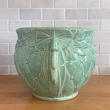 Load image into Gallery viewer, Large vintage Tierra Cushion jardiniere planter pot, aqua gloss glaze, features an overlapping floral leaf pattern around the top rim, a diamond quilted body and ribbon handles. Crafted by McCoy Pottery, USA, 1950s. A must-have for any McCoy collector or gardener!

In excellent condition, free from chips, cracks or repairs, with a manufacturer's glaze pops and like defects, see photo. Maker's mark.

Measures 9 x 7 1/4 inches
