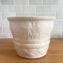 Load image into Gallery viewer, Vintage art deco matte white ceramic jardiniere planter featuring repeating columns of stacked palm leaves atop a basket weave pattern. Crafted by Robinson Ransbottom Pottery Co., USA, 1930s. A beautiful piece to add to your art pottery collection!

In excellent condition, no chips/cracks/repairs. Typical manufacturing glaze pops. Unmarked.

Measures 7 3/8 x 5 1/2 inches
