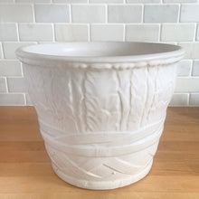 Load image into Gallery viewer, Vintage art deco matte white ceramic jardiniere planter featuring repeating columns of stacked palm leaves atop a basket weave pattern. Crafted by Robinson Ransbottom Pottery Co., USA, 1930s. A beautiful piece to add to your art pottery collection!

In excellent condition, no chips/cracks/repairs. Typical manufacturing glaze pops. Unmarked.

Measures 10 1/2 x 8 1/2 inches
