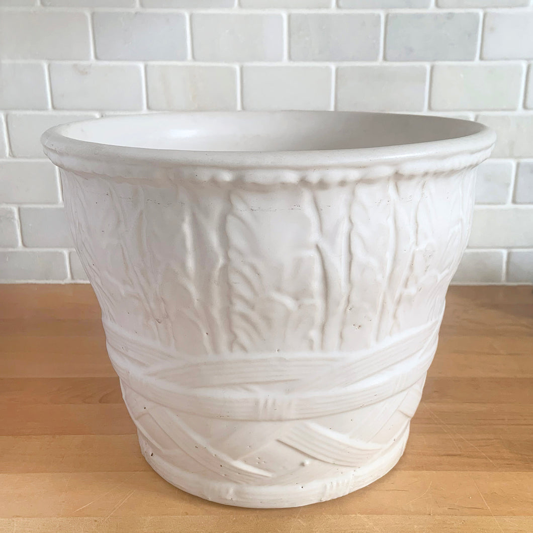 Vintage art deco matte white ceramic jardiniere planter featuring repeating columns of stacked palm leaves atop a basket weave pattern. Crafted by Robinson Ransbottom Pottery Co., USA, 1930s. A beautiful piece to add to your art pottery collection!

In excellent condition, no chips/cracks/repairs. Typical manufacturing glaze pops. Unmarked.

Measures 10 1/2 x 8 1/2 inches