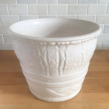 Load image into Gallery viewer, Vintage art deco matte white ceramic jardiniere planter featuring repeating columns of stacked palm leaves atop a basket weave pattern. Crafted by Robinson Ransbottom Pottery Co., USA, 1930s. A beautiful piece to add to your art pottery collection!

In excellent condition, no chips/cracks/repairs. Typical manufacturing glaze pops. Unmarked.

Measures 10 1/2 x 8 1/2 inches
