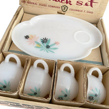 Load image into Gallery viewer, This delightful vintage mid-century era Atomic Flower eight piece milk glass snack plate and cup set captures the perfect balance between classic style and sophistication. The plates are offset oval shaped and both plate and cup feature a sweet pattern of florals in shades of turquoise, pink, yellow and black. Crafted by Federal Glass, USA, circa 1950s. New old stock in original box. In like-new vintage condition, no chips, cracks or wear.

Snack plates measure 7x10 inches Cups measure 3 1/4x2 1/2 inches
