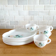 Load image into Gallery viewer, This delightful vintage mid-century era Atomic Flower eight piece milk glass snack plate and cup set captures the perfect balance between classic style and sophistication. The plates are offset oval shaped and both plate and cup feature a sweet pattern of florals in shades of turquoise, pink, yellow and black. Crafted by Federal Glass, USA, circa 1950s. New old stock in original box. In like-new vintage condition, no chips, cracks or wear.

Snack plates measure 7x10 inches Cups measure 3 1/4x2 1/2 inches
