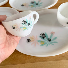 Load image into Gallery viewer, This delightful vintage mid-century era Atomic Flower eight piece milk glass snack plate and cup set captures the perfect balance between classic style and sophistication. The plates are offset oval shaped and both plate and cup feature a sweet pattern of florals in shades of turquoise, pink, yellow and black. Crafted by Federal Glass, USA, circa 1950s. New old stock in original box. In like-new vintage condition, no chips, cracks or wear.

Snack plates measure 7x10 inches Cups measure 3 1/4x2 1/2 inches
