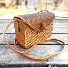 Load image into Gallery viewer, Lovely lightweight natural eastern Bali Ata Grass cross-body purse with loop closure, leather strap and cotton lining. Handcrafted by artisans using time-honoured techniques for Maker&#39;s Supply in Indonesia. Perfect for spring and summer, it adds a touch of casual sophistication to any feminine wardrobe.

The lining may have a water stain, but otherwise the purse is like-new and includes the original tags.

Measures 8 3/4 x 3 1/4 x 6 inches (28 inches with strap)
