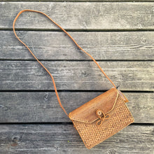 Load image into Gallery viewer, Lovely lightweight natural eastern Bali Ata Grass cross-body purse with loop closure, leather strap and cotton lining. Handcrafted by artisans using time-honoured techniques for Maker&#39;s Supply in Indonesia. Perfect for spring and summer, it adds a touch of casual sophistication to any feminine wardrobe.

The lining may have a water stain, but otherwise the purse is like-new and includes the original tags.

Measures 8 3/4 x 3 1/4 x 6 inches (28 inches with strap)
