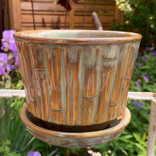 Load image into Gallery viewer, Vintage blended exotic brown glazed Bamboo ceramic planter with attached saucer from the Green Thumb Line. Crafted by McCoy Pottery, 1970s. A hard-to-find planter in a rare glaze. A must have for any art pottery collector. A sweet piece for your favourite houseplant or succulent.

In excellent vintage condition, no chips/cracks/repairs, typical age-related crazing and manufacturer's glaze pops. Maker's marks.

Measures 5 1/2 x 4 1/2 inches
