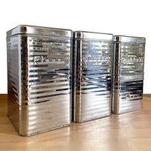 Load image into Gallery viewer, Angled front view of Vintage Lincoln BeautyWare 4-piece chrome kitchen canister set, embossed Flour Sugar Coffee Tea lettering, ribbed steel, 1940s USA
