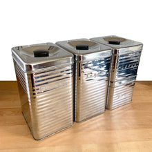 Load image into Gallery viewer, Elevated angled view of Vintage Lincoln BeautyWare 4-piece chrome kitchen canister set, embossed Flour Sugar Coffee Tea lettering, ribbed steel, 1940s USA
