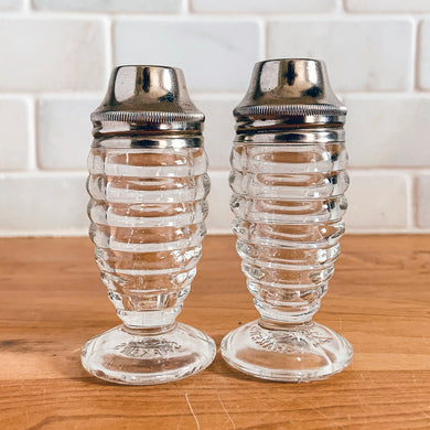 These shakers give off all the vintage vibes! Pressed clear glass of concentric circles or stacked rings on a round foot with silver-toned metal lids plus interior red disc. Part of Line #3530, produced by Hazel-Atlas Glass, USA, circa 1930s.  In excellent condition, free from chips/cracks. Normal age-related wear. Marked 