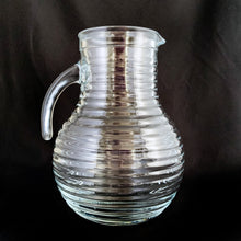 Load image into Gallery viewer, This vintage ribbed or beehive open handle pressed glass pitcher is perfect for water, lemonade, ice tea or the bevvy of your choosing. Made in Italy, circa 1960s.  In excellent condition, free from chips/cracks. Marked &quot;Italy&quot;  Measures 5 1/2 x 8 1/8 inches  Capacity 68 ounces   
