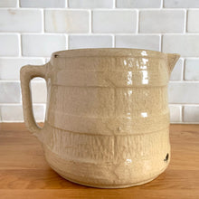 Load image into Gallery viewer, Vintage natural yellow ware strapped barrel milk pitcher featuring black lily in bas relief with rope style handle, No. 21171. Crafted by Robinson Ransbottom Pottery Co., USA, 1930s. A beautiful piece of primitive farmhouse tableware to enhance your home&#39;s decor and a wonderful addition to any art pottery collection!

Measures 5 1/4 x 5 1/4 inches. In as found vintage condition, chip to rim, no cracks/repairs, glaze wear at the spout, age-related crazing and glaze pops. Unmarked. Capacity 48 ounces
