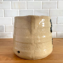 Load image into Gallery viewer, Vintage natural yellow ware strapped barrel milk pitcher featuring black lily in bas relief with rope style handle, No. 21171. Crafted by Robinson Ransbottom Pottery Co., USA, 1930s. A beautiful piece of primitive farmhouse tableware to enhance your home&#39;s decor and a wonderful addition to any art pottery collection!

Measures 5 1/4 x 5 1/4 inches. In as found vintage condition, chip to rim, no cracks/repairs, glaze wear at the spout, age-related crazing and glaze pops. Unmarked. Capacity 48 ounces
