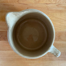 Load image into Gallery viewer, Vintage natural yellow ware strapped barrel milk pitcher featuring black lily in bas relief with rope style handle, No. 21171. Crafted by Robinson Ransbottom Pottery Co., USA, 1930s. A beautiful piece of primitive farmhouse tableware to enhance your home&#39;s decor and a wonderful addition to any art pottery collection!

Measures 5 1/4 x 5 1/4 inches. In as found vintage condition, chip to rim, no cracks/repairs, glaze wear at the spout, age-related crazing and glaze pops. Unmarked. Capacity 48 ounces

