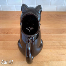 Load image into Gallery viewer, Vintage mid-century era redware ceramic cat creamer, featuring a figural seated cat, glazed is glossy black with a brown undertone and hand painted green eyes. Crafted by Shafford, Japan, 1950s. This kitschy creamer pours from the open mouth and works equally well as a decorative display piece. A solid example of postwar Japanese export ceramics with playful character and collectible appeal.

In excellent condition, no chips, cracks or repairs. Unmarked

Measures 5 1/4 x 3 x 5 1/2 inches
