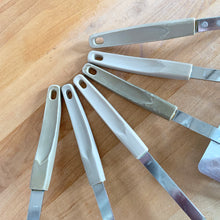 Load image into Gallery viewer, Close-up of the back of six cream melamine handles from vintage Japanese kitchen utensil set
