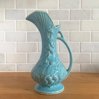 Vintage Art Deco gloss blue Rustic Line handled pitcher vase with embossed grapevines. Crafted by McCoy Pottery, 1945. This rare piece is must for any McCoy art pottery collector!

In excellent vintage condition, no chips/cracks/repairs. Maker's mark.

Measures 5 1/4 x 9 inches