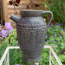 Load image into Gallery viewer, Rare vintage blue stoneware batter jug or pitcher decorated with panels of a figure playing a lyre against a stippled ground with decorative details. Crafted by Robinson Ransbottom Pottery Co., USA, 1920s.

In good used vintage condition, minor flea bites to the rim and foot. Normal age-related crazing. Unmarked.

Measures 9 x 10 1/2 inches (incl. spout/handle)
