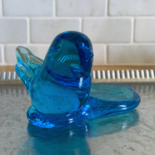 Load image into Gallery viewer, Lovely vintage hand blown art glass bluebird featuring a platform to hold a tea light or votive candle holder. Designed by artisan Leo Ward, his signature is on the bottom with the year 1987. Mr. Ward was the creator of Arkansas&#39; Bluebird of Happiness and owner of Terra Studios in Arkansas. He crafted these much beloved bluebirds until his death at 89.  In excellent condition, free from chips or cracks. Measures 4 x 3 3/4 x 2 1/2 inches
