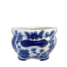 Load image into Gallery viewer, Side view of Bombay Company blue and white chinoiserie oval jardiniere, showing a fan-tailed butterfly and dense floral spray pattern with cobalt handles and four feet
