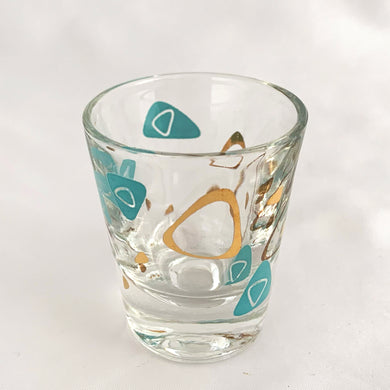 Vintage mid-century design in this turquoise and 22kt gold Boomerang Amoeba shot glass. Crafted by Federal Glass, USA, 1960s. A fabulous example of atomic style, this wee cocktail glass will amp up any bar cart and makes a fabulous addition to any barware collection.

In excellent condition, no chips, minor wear.

Measures 2 x 2 1/4 inches

Capacity 1 oz