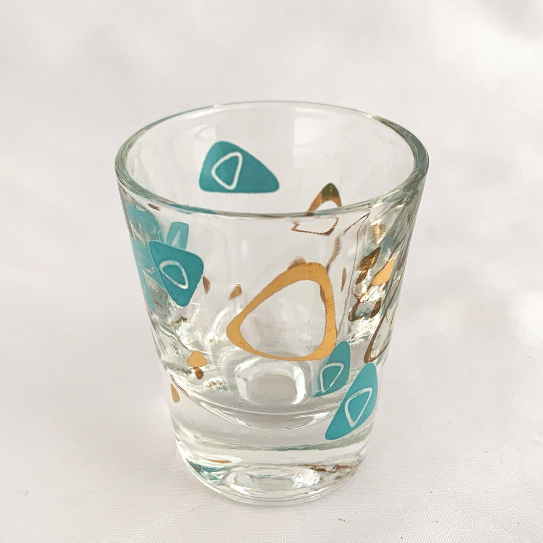 Vintage mid-century design in this turquoise and 22kt gold Boomerang Amoeba shot glass. Crafted by Federal Glass, USA, 1960s. A fabulous example of atomic style, this wee cocktail glass will amp up any bar cart and makes a fabulous addition to any barware collection.

In excellent condition, no chips, minor wear.

Measures 2 x 2 1/4 inches

Capacity 1 oz