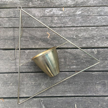 Load image into Gallery viewer, This is the real deal! Fabulous vintage triangular shaped brass metal wire plant hanger with fixed planter pot. They can be hung individually, in tandem or aligned for that added wow factor! Crafted in France, 1960s. A sweet way to add mid-century bohemian style to your home decor and the perfect gift for any plant lover!

In good vintage condition with original sticker. Age appropriate wear to the pot.

Hanging frame measures 20 3/4 x 33 inches, pot measures 6 1/8 x 5 1/8 inches
