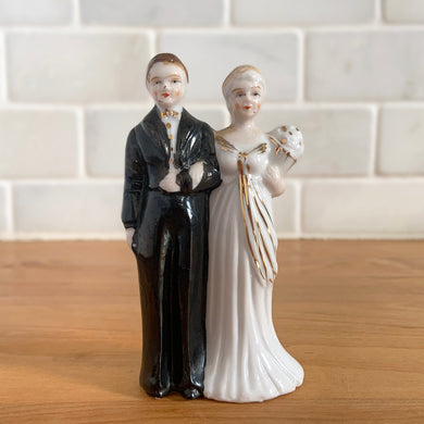 Vintage Art Deco style bride and groom ceramic wedding cake topper figurine in classic black and white with gold gilt. Crafted by Lefton, Japan, 1940s. A lovely piece to adorn any wedding cake. Also makes a great prop for wedding themed photography.

In excellent condition, no chips, minor wear.

Measures 1 7/8 x 1 1/8 x 3 1/2 inches