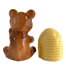 Load image into Gallery viewer, Vintage brown bear hugging a beehive ceramic salt and pepper shakers with plastic stoppers. Japan, 1970s. Add these adorable kitschy shakers to your collection!

In excellent condition, no chips/cracks/repairs. Marked Japan.

Bear measures 3 1/4 x 2 1/2 x 4 5/8 inches

Beehive measures 2 1/4 x 2 7/8 inches

