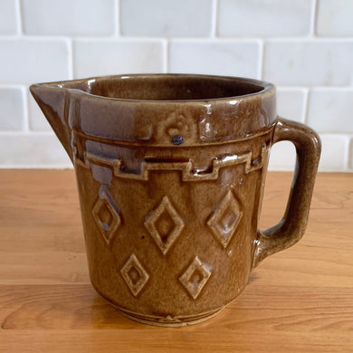 Vintage glossy caramel brown stoneware pitcher featuring a castle turret with diamonds detail. Crafted by Monmouth Western Stoneware, USA, 1920s. Add this utilitarian piece to your farmhouse decor or art pottery collection!

In excellent condition, no chips/cracks/repairs, age-related crazing. Unmarked.

Measures 4 1/2 x 5 inches